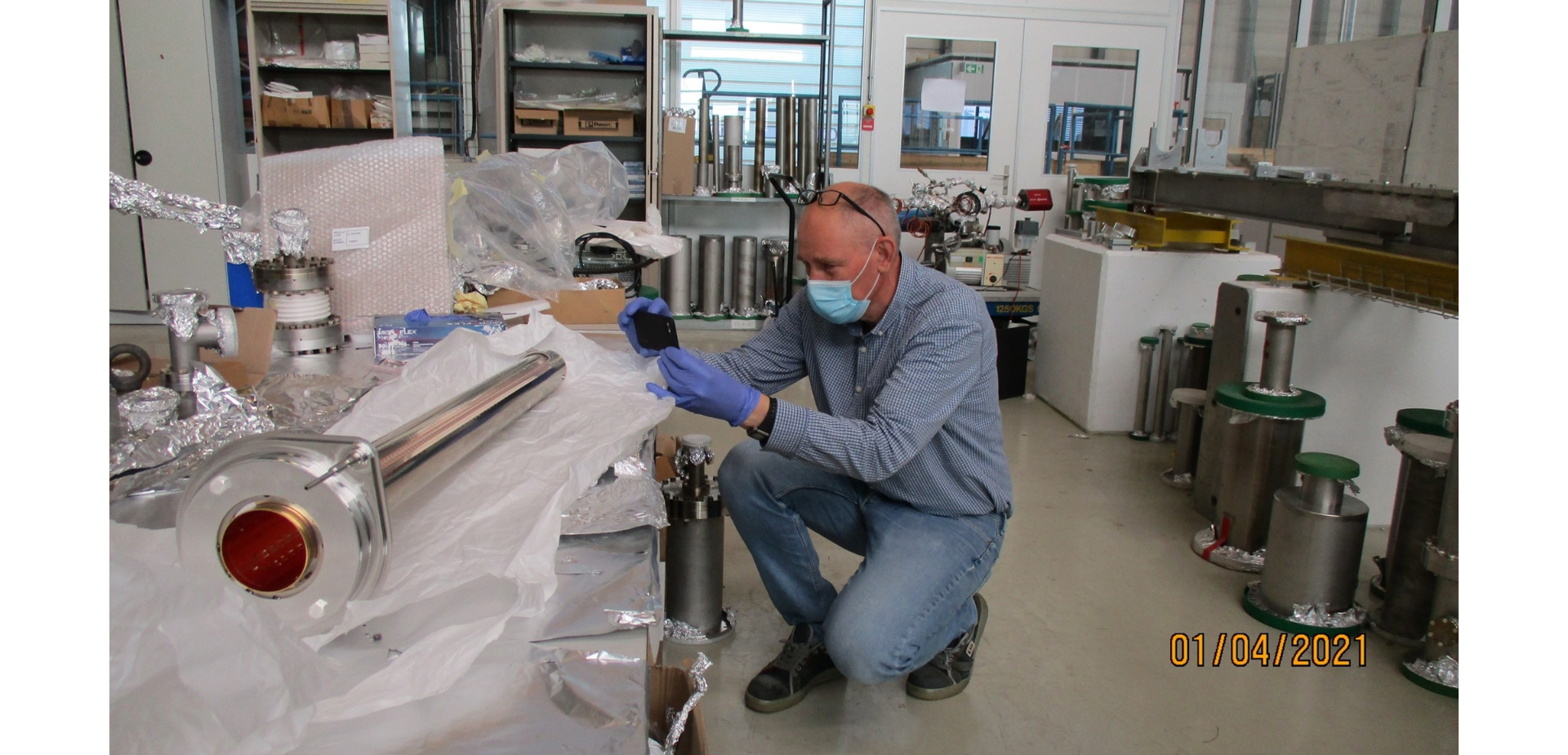 man in blue with mask and gloves working on cylindrical equipment